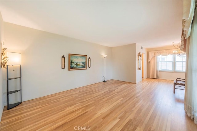 spare room featuring a chandelier and light hardwood / wood-style floors