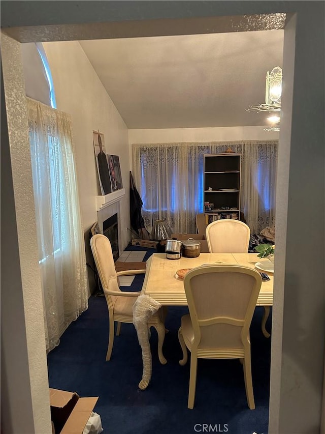 dining area featuring vaulted ceiling and a tile fireplace