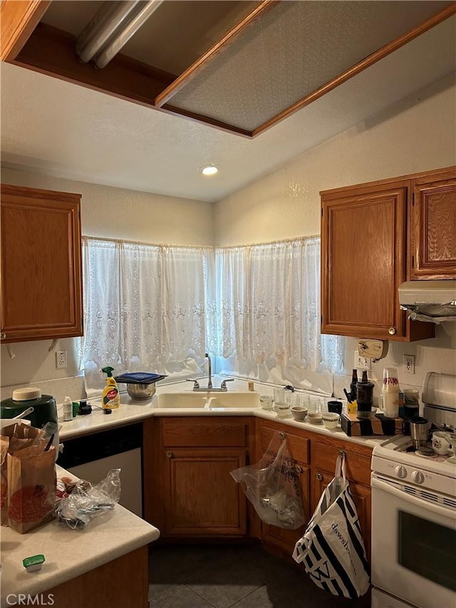 kitchen with sink, dark tile patterned floors, stainless steel dishwasher, and white stove