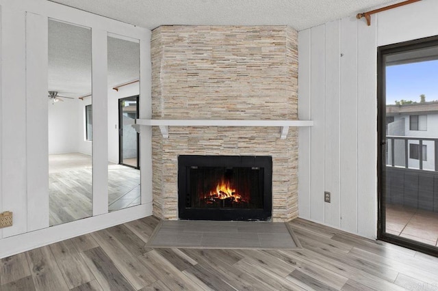 details with ceiling fan, wood-type flooring, a textured ceiling, and a fireplace