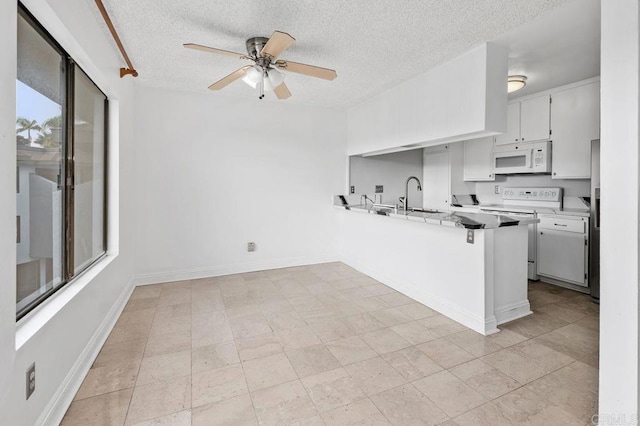 kitchen with ceiling fan, electric range oven, kitchen peninsula, sink, and white cabinetry