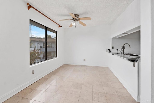 tiled spare room featuring a textured ceiling, ceiling fan, and sink