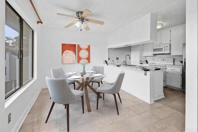 dining area featuring ceiling fan, sink, and a textured ceiling