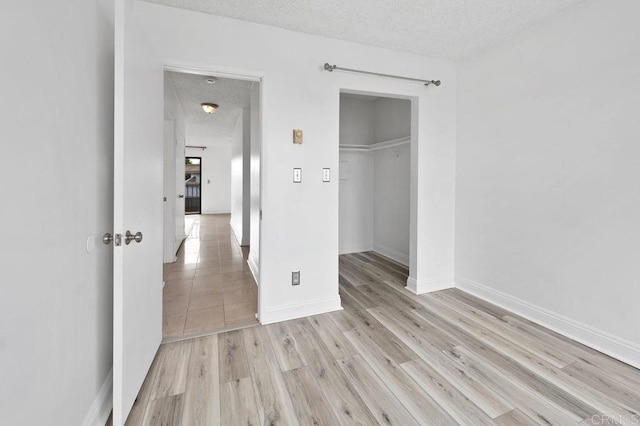 unfurnished bedroom with a closet, a textured ceiling, and light hardwood / wood-style flooring