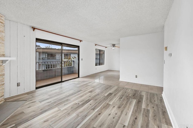 unfurnished room featuring a textured ceiling, ceiling fan, and light wood-type flooring