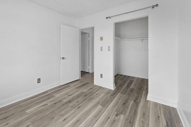 unfurnished bedroom with a textured ceiling, a closet, and light hardwood / wood-style flooring