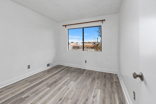 empty room featuring a textured ceiling and light wood-type flooring