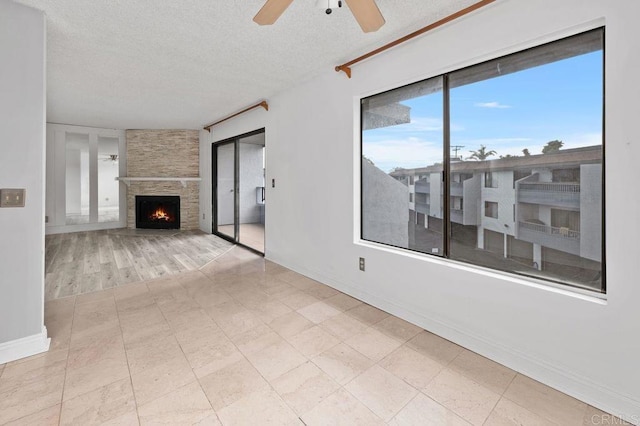 living room featuring a textured ceiling, ceiling fan, and a large fireplace