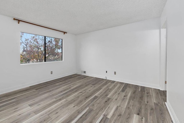 empty room with a textured ceiling and light hardwood / wood-style floors