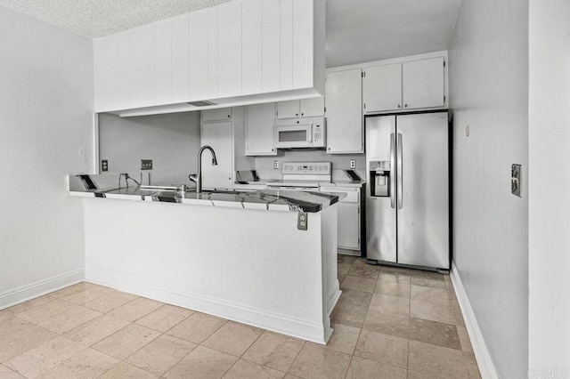 kitchen with a textured ceiling, sink, kitchen peninsula, and white appliances