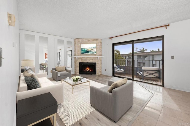 living room with a textured ceiling, light tile patterned floors, and a stone fireplace