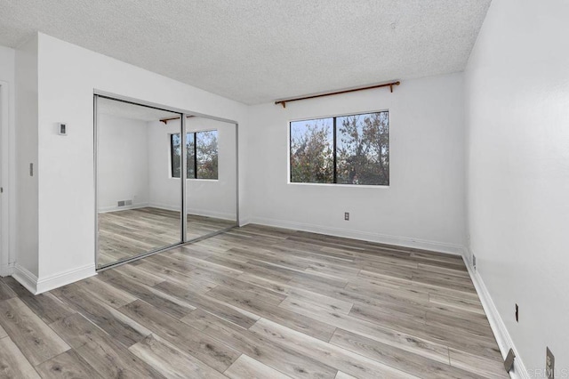 unfurnished bedroom featuring a closet, a textured ceiling, and light hardwood / wood-style floors