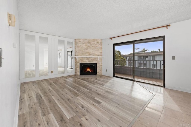 unfurnished living room with a large fireplace, a textured ceiling, and wood finished floors