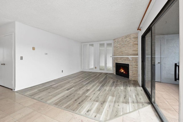 unfurnished living room featuring light wood finished floors, a fireplace, and a textured ceiling