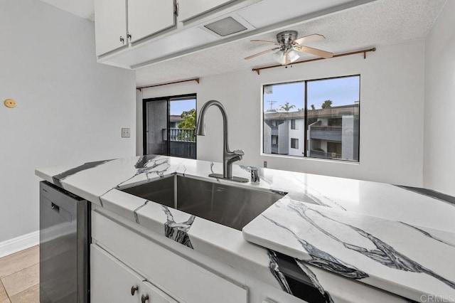 kitchen with a sink, light stone counters, dishwasher, ceiling fan, and white cabinets