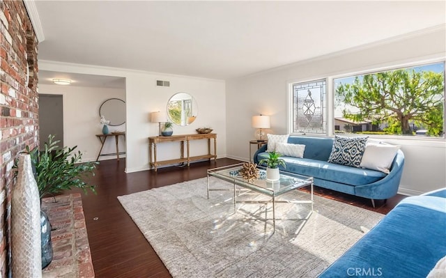 living room with dark hardwood / wood-style flooring, ornamental molding, and a brick fireplace