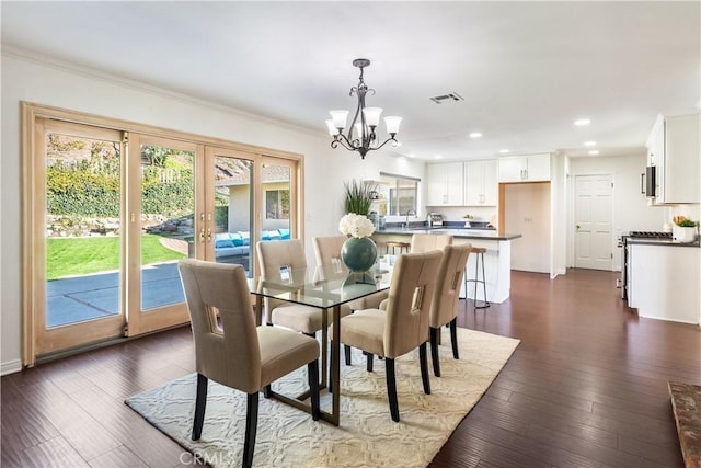 dining room with dark hardwood / wood-style flooring, french doors, an inviting chandelier, sink, and ornamental molding