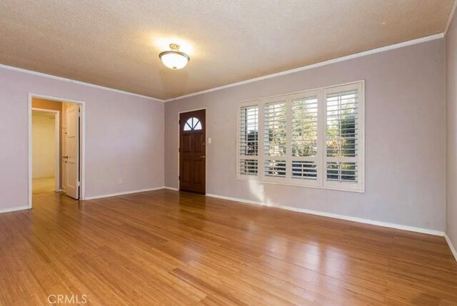 entryway featuring hardwood / wood-style flooring, plenty of natural light, a textured ceiling, and ornamental molding