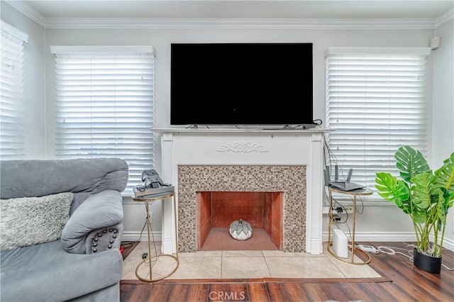 living room with hardwood / wood-style floors, ornamental molding, and a tiled fireplace