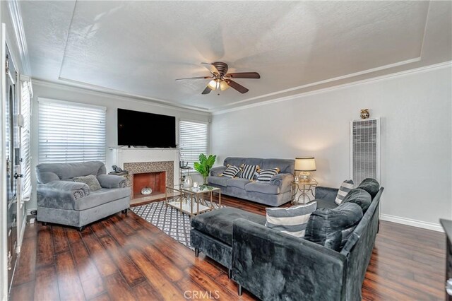 living room featuring a raised ceiling, ceiling fan, dark wood-type flooring, and a tiled fireplace