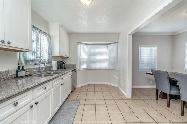 kitchen with light stone counters, sink, white cabinets, and dishwasher