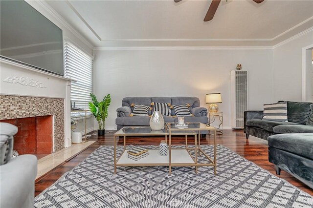 living room featuring ceiling fan, a tiled fireplace, crown molding, and hardwood / wood-style floors