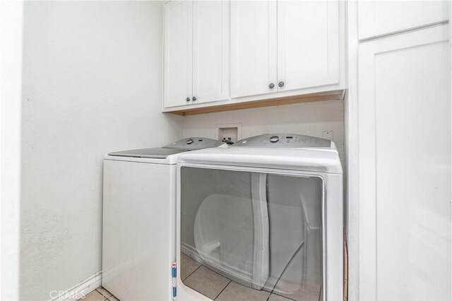 laundry area with washer and dryer, cabinets, and light tile patterned floors