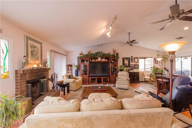 living room with lofted ceiling, ceiling fan, a brick fireplace, light hardwood / wood-style floors, and rail lighting