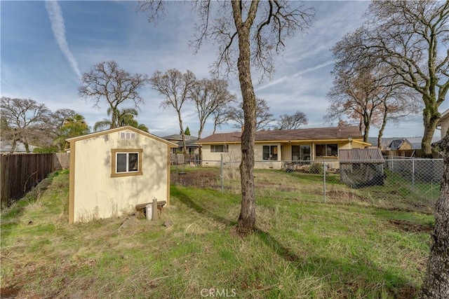 rear view of property featuring a yard and a storage shed