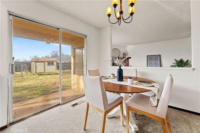 dining space featuring an inviting chandelier and a textured ceiling