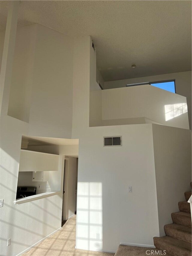 staircase featuring a towering ceiling and carpet floors