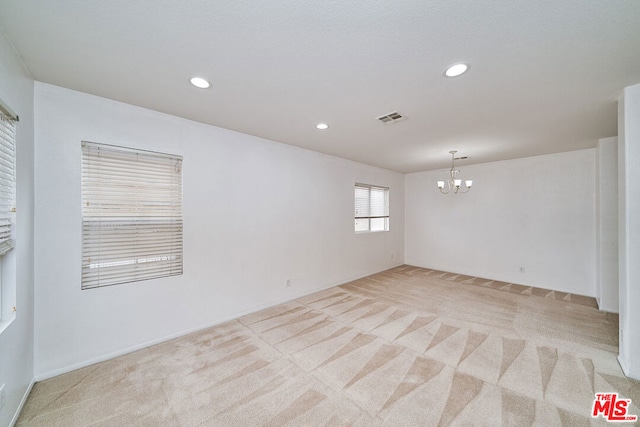 unfurnished room featuring light carpet, a fireplace, and a chandelier