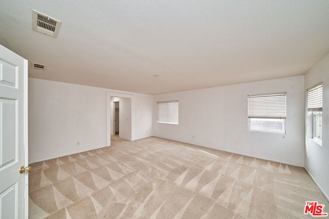 carpeted spare room with a textured ceiling