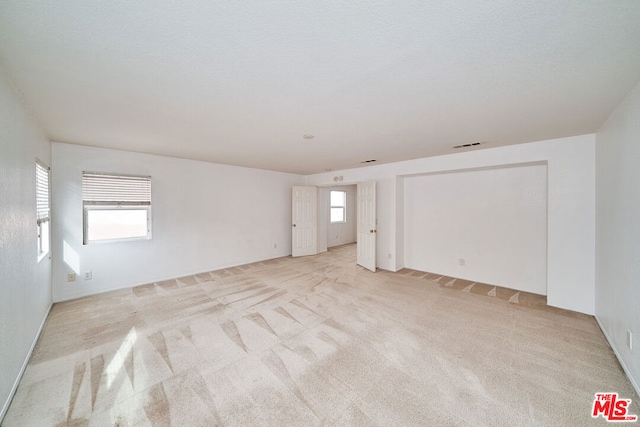 carpeted empty room featuring a textured ceiling