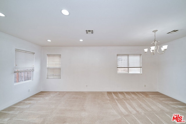 empty room with light carpet and a chandelier