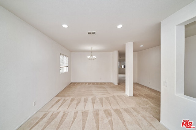 carpeted empty room featuring a notable chandelier