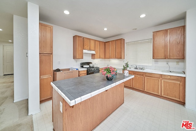 kitchen featuring a breakfast bar area, a kitchen island, black gas range oven, and sink