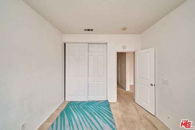 bedroom with light carpet and a closet