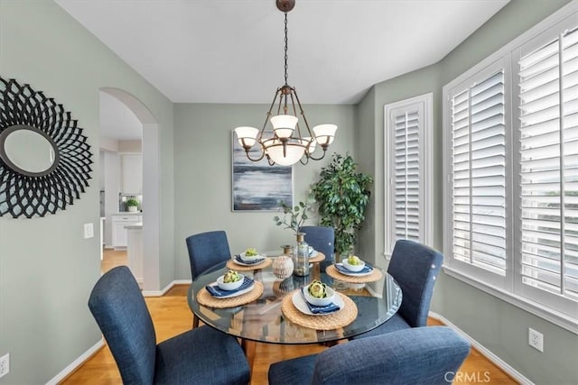 dining area featuring a notable chandelier, a healthy amount of sunlight, and light wood-type flooring