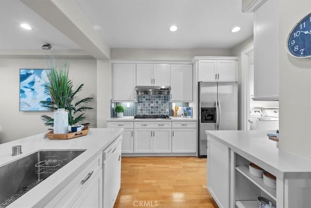 kitchen with white cabinetry, sink, stainless steel refrigerator with ice dispenser, white dishwasher, and washer and dryer