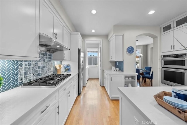 kitchen featuring white cabinets, decorative backsplash, light hardwood / wood-style floors, and appliances with stainless steel finishes