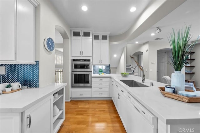 kitchen featuring decorative backsplash, double oven, sink, dishwasher, and white cabinetry