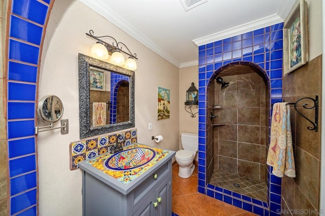 bathroom featuring a tile shower, toilet, vanity, and crown molding