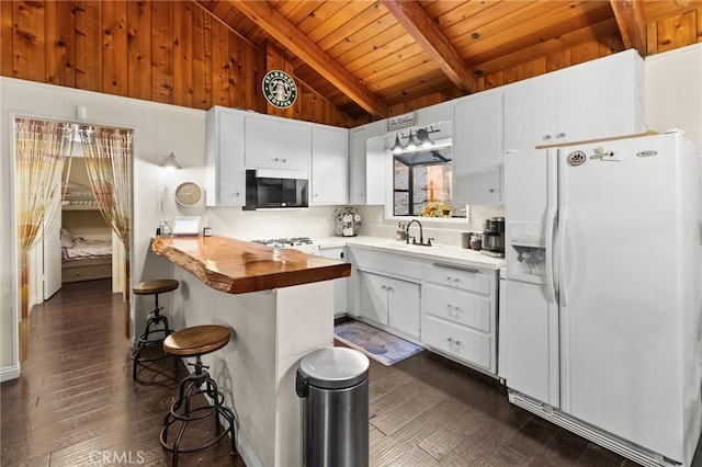 kitchen with white fridge with ice dispenser, white cabinets, a kitchen bar, butcher block counters, and beam ceiling