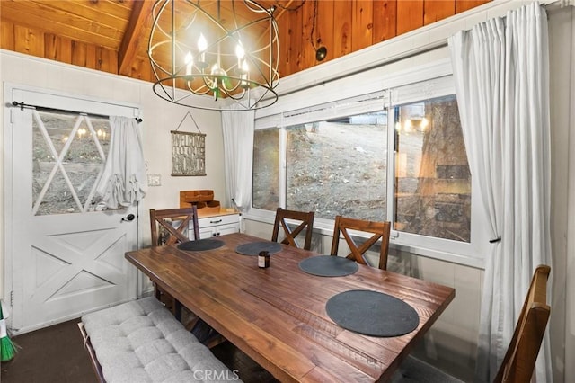 dining area featuring lofted ceiling with beams, wood ceiling, wooden walls, and an inviting chandelier