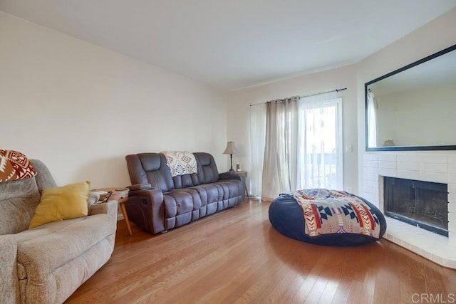 living room featuring a brick fireplace and hardwood / wood-style flooring