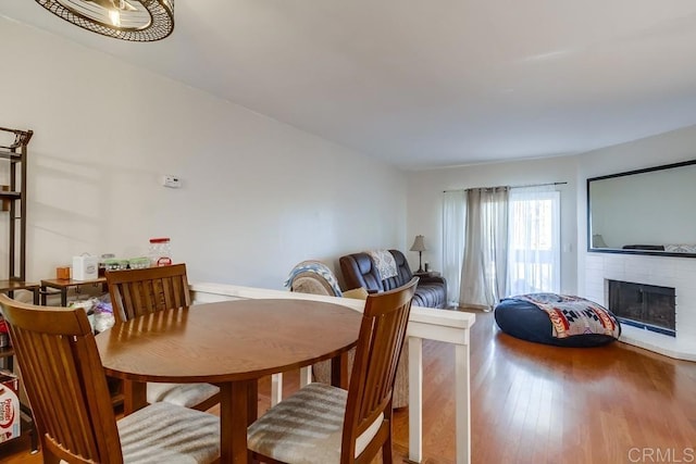 dining room with a brick fireplace and wood-type flooring