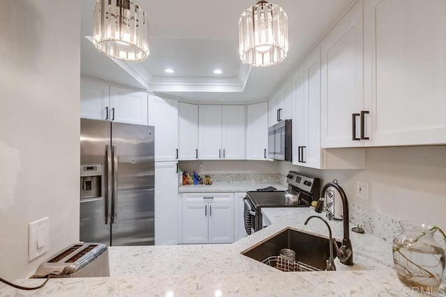 kitchen featuring a tray ceiling, white cabinetry, appliances with stainless steel finishes, and an inviting chandelier