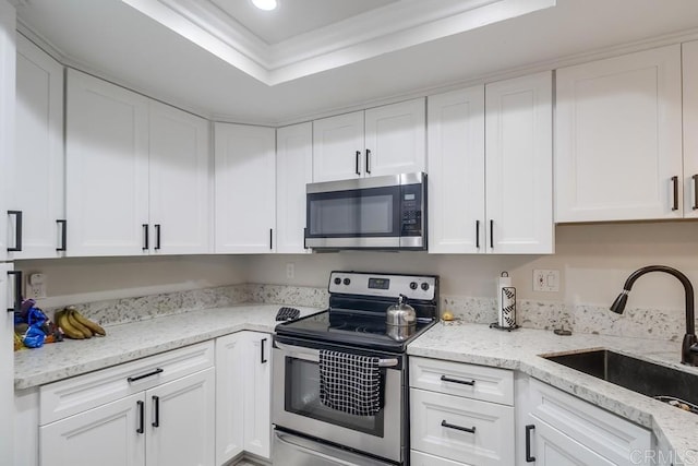 kitchen with stainless steel appliances, white cabinets, a tray ceiling, and sink