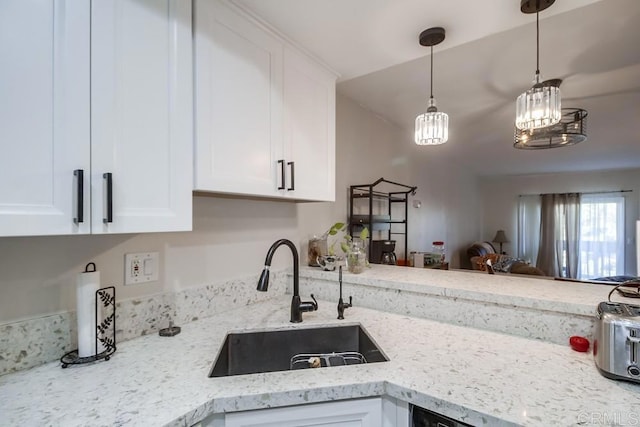 kitchen featuring light stone countertops, pendant lighting, white cabinets, sink, and kitchen peninsula